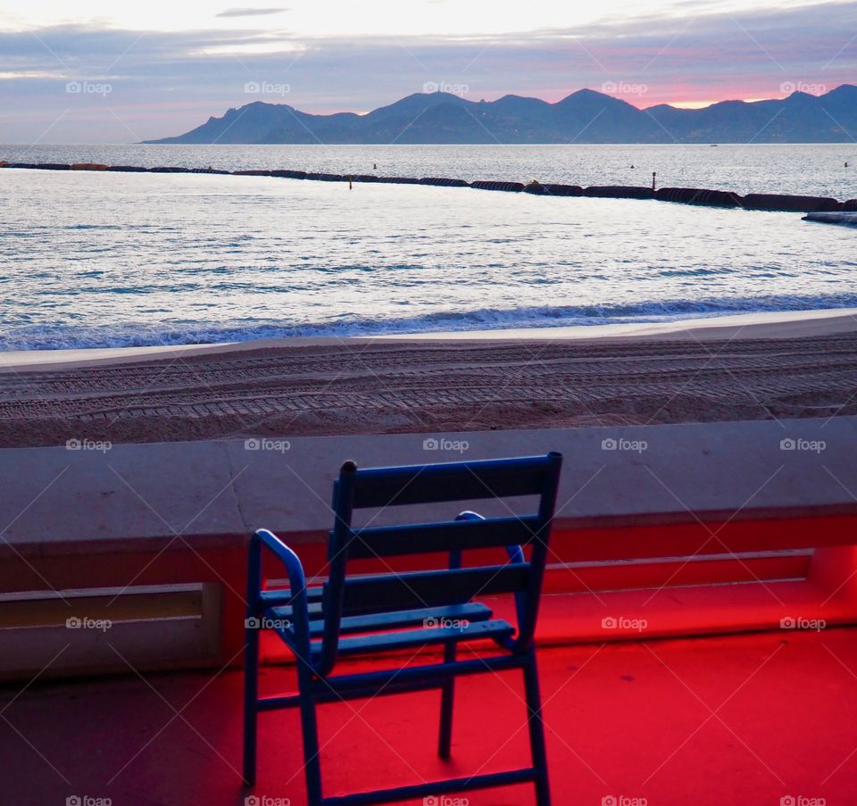 Blue chair facing the sea on the Croisette in Cannes, France.