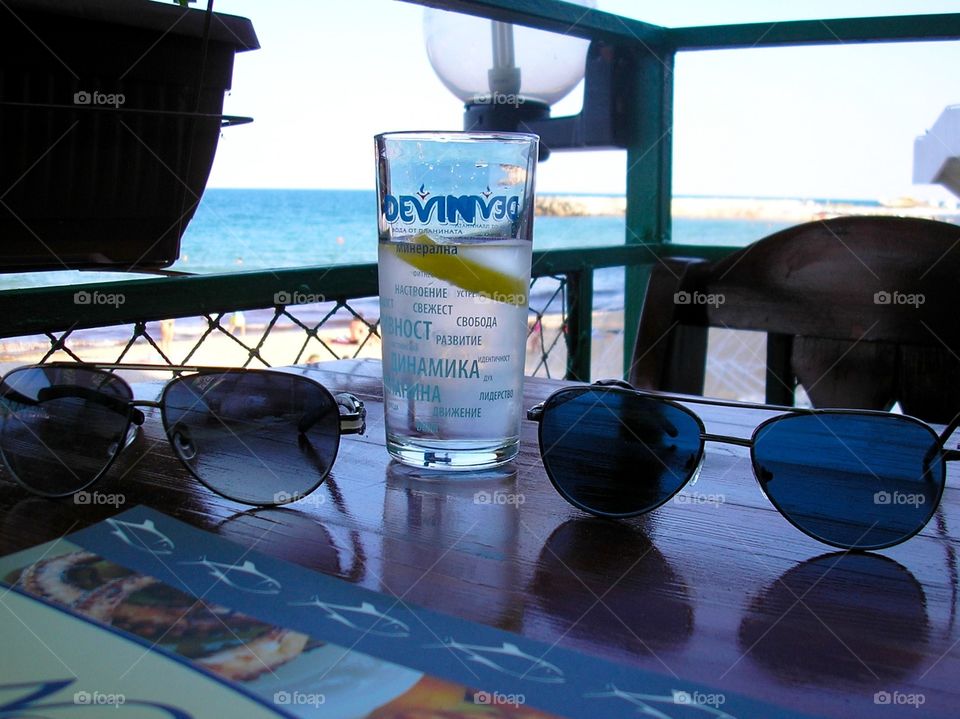 Two glasses and a glass of water on a table in a sea coast cafe