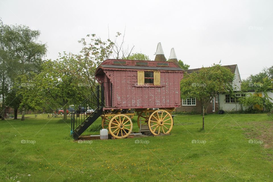 Old wood gypsy caravan that is pulled by horses with oast house 