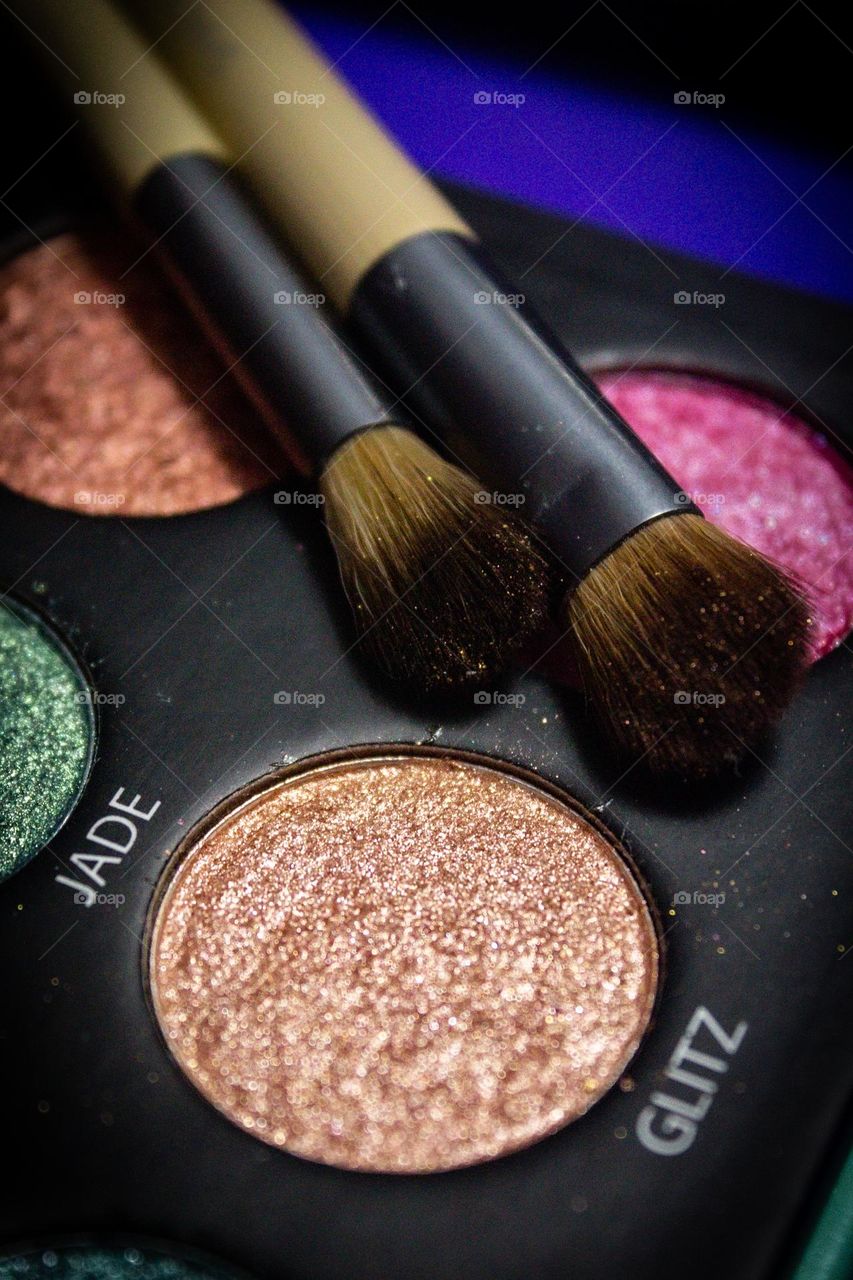 All glammed up! Brightly colored glittery eye shadow with a blender and shade brush for application.