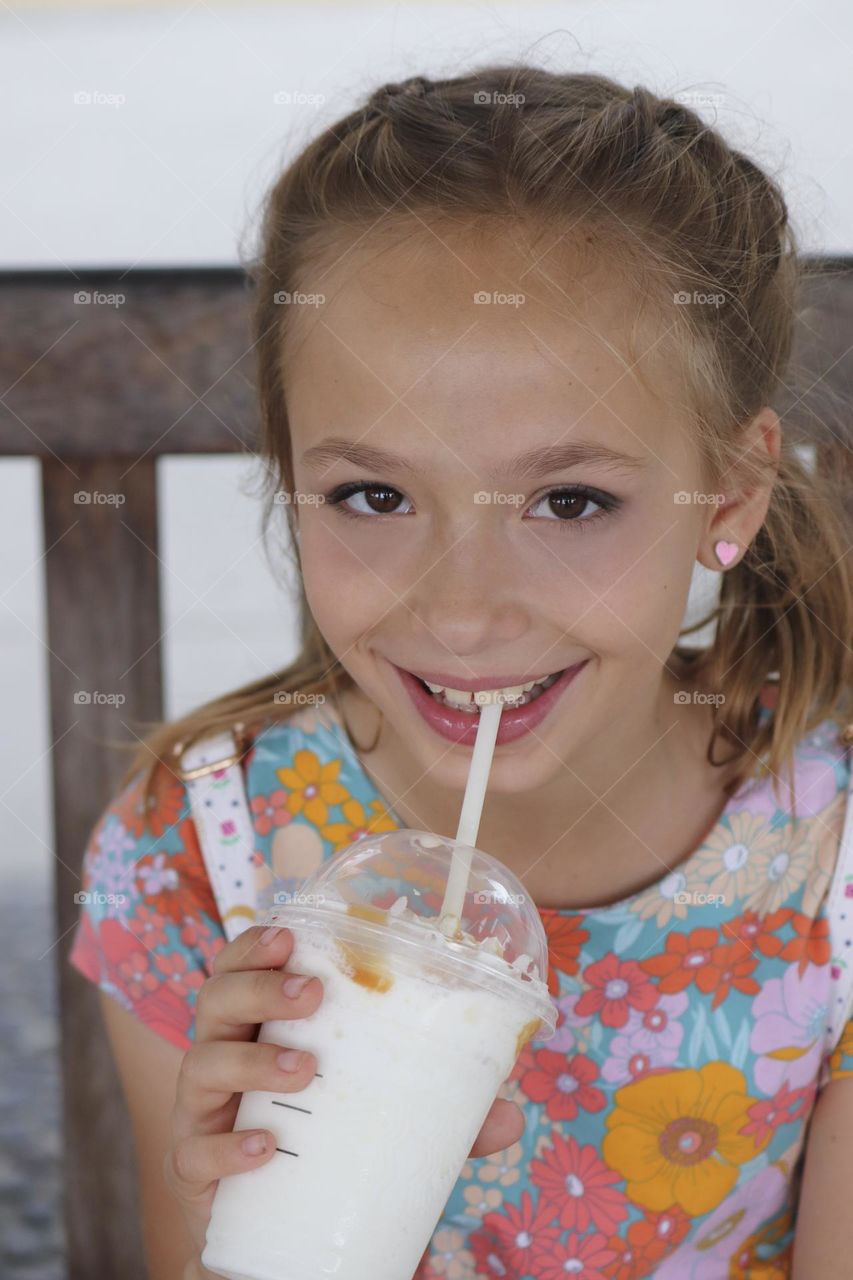 Smiling young girl drunk cold refreshing drink.