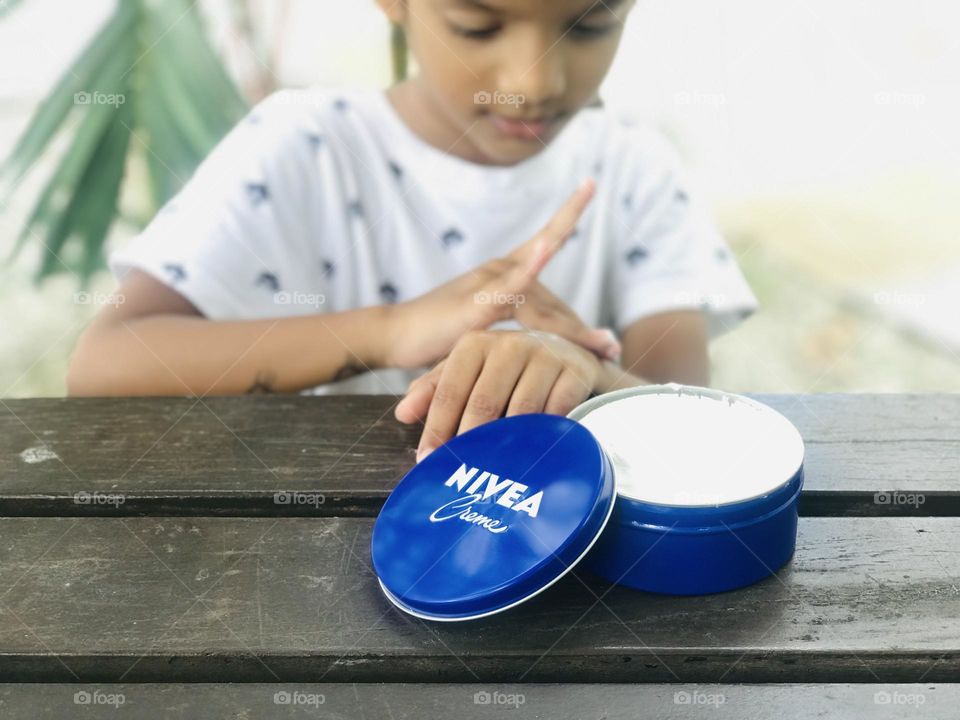 A boy applying Nivea cream to his hand.