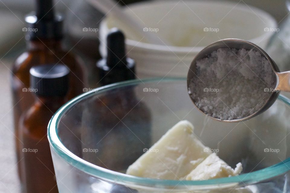 Pouring beeswax granules into other ingredients to be weighed for homemade skin care products 