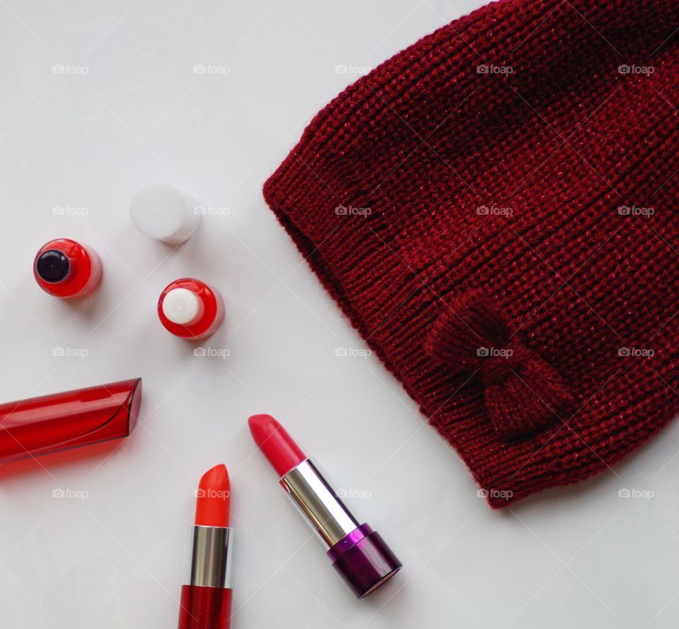 Red color of cosmetics and wool hat on white background.
