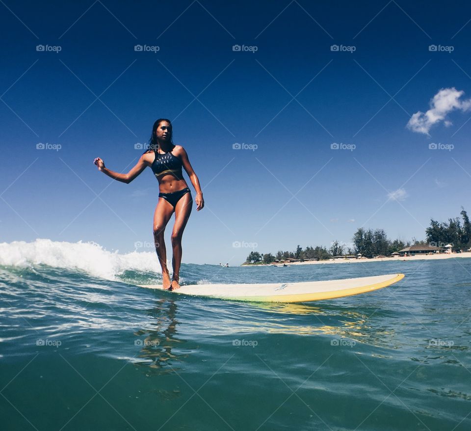 Slim woman surfing in sea