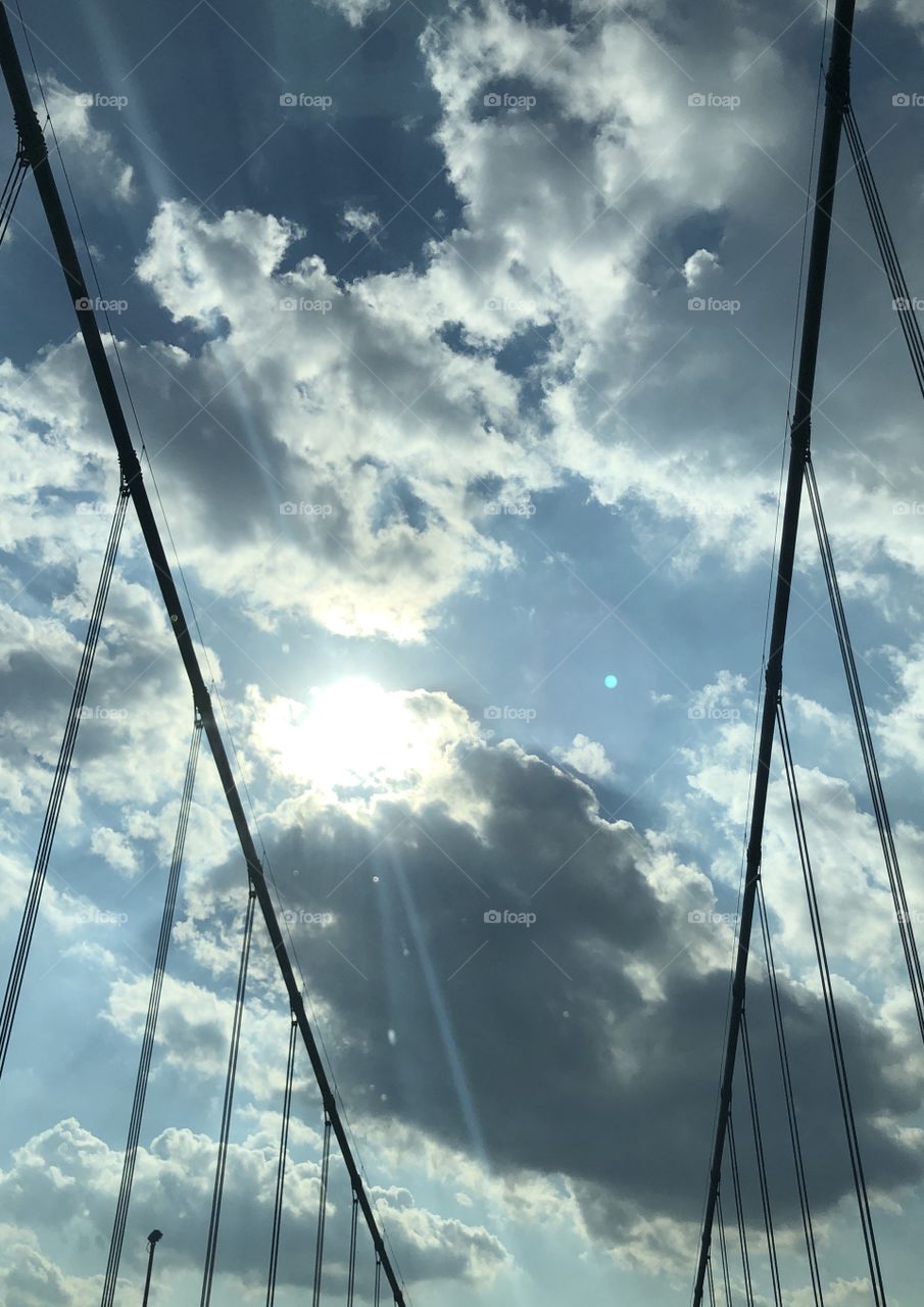 Sun beaming through the clouds over a bridge 