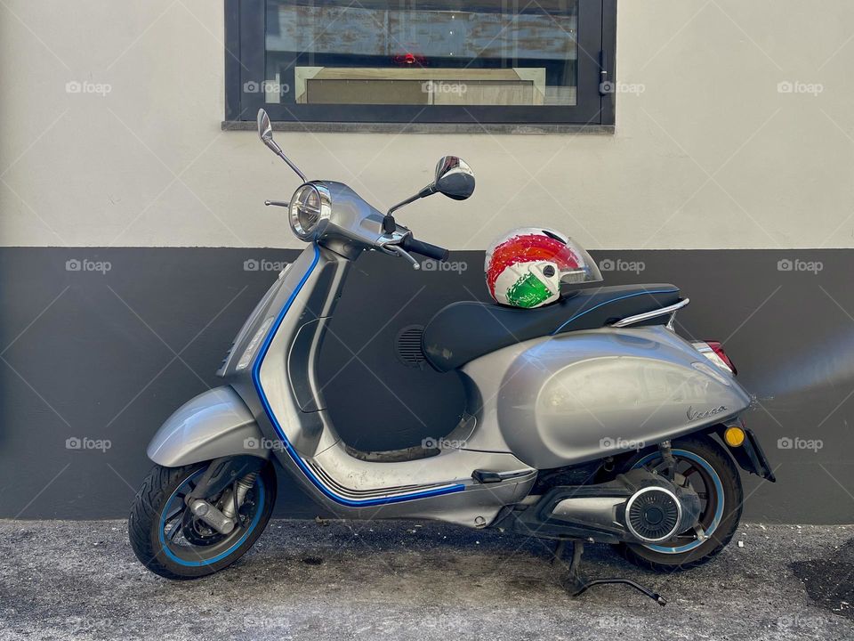 Silver scooter with helmet near the wall