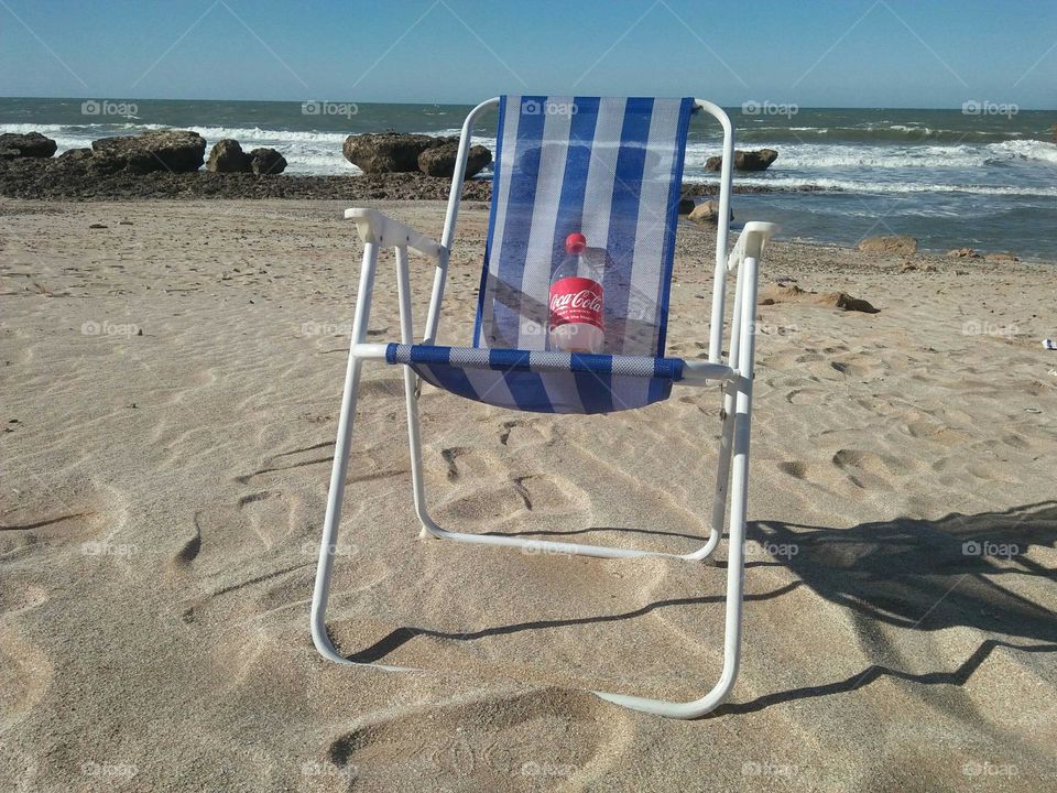 Sweety Cocacola on a chair agaunst the sea.