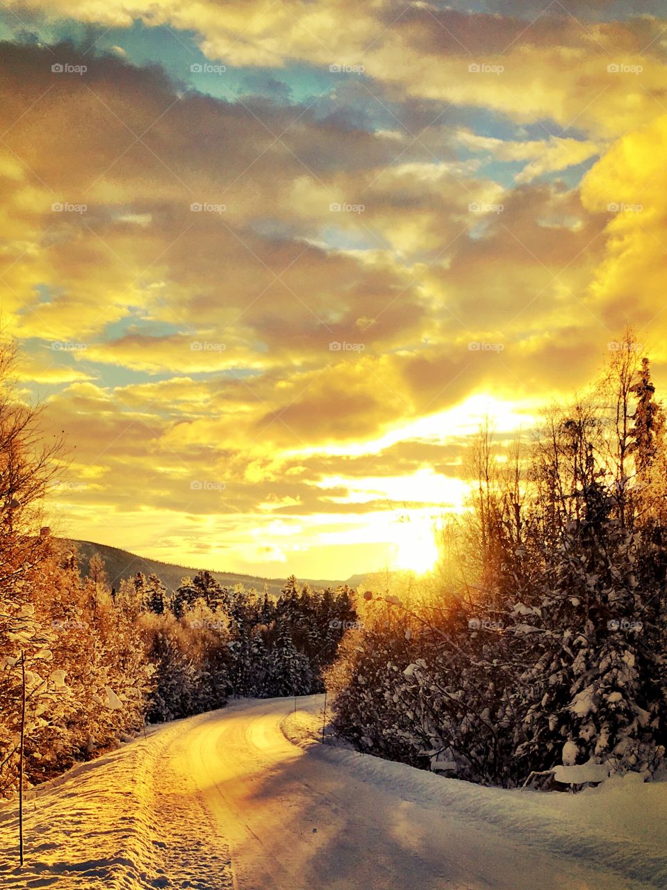 View of snow covered empty road during sunset