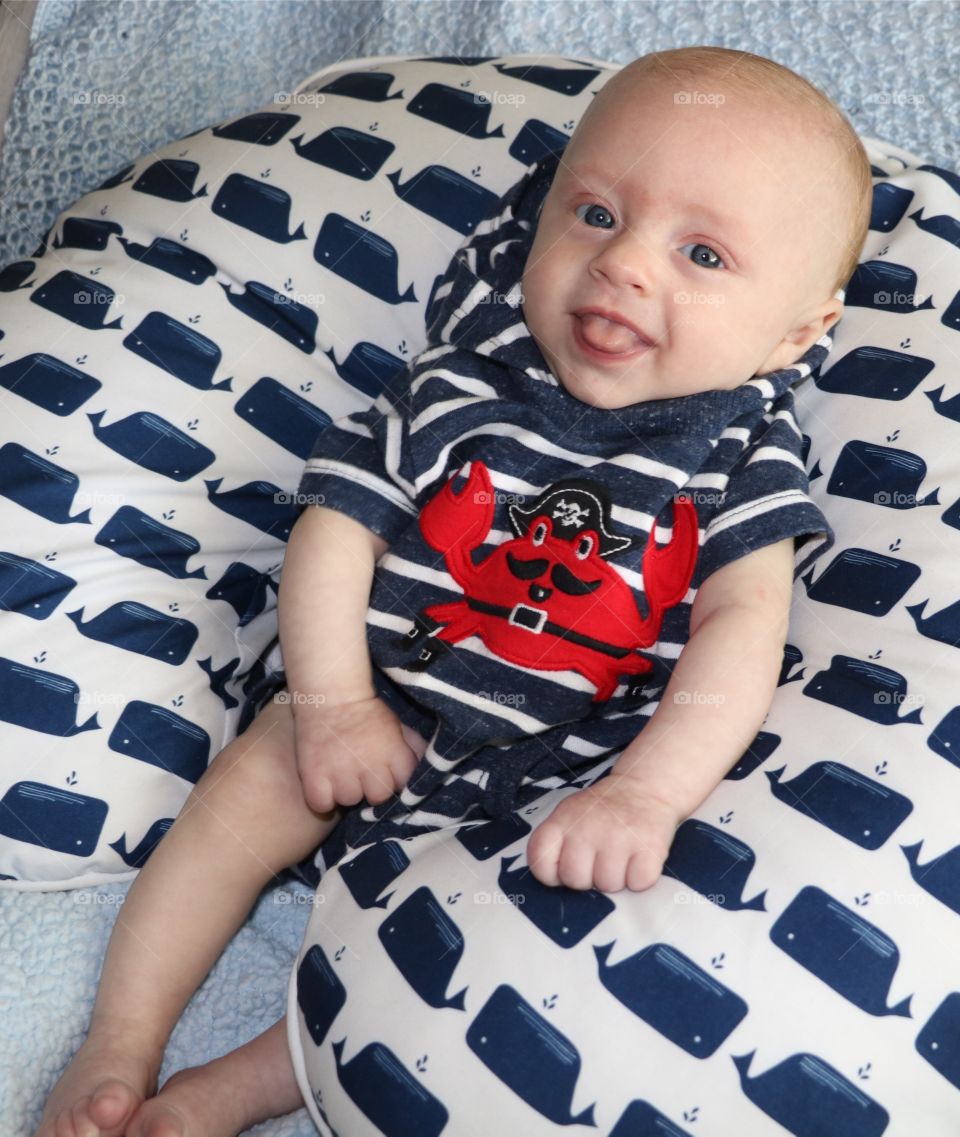 Adorable baby boy smiling and posing for the camera.