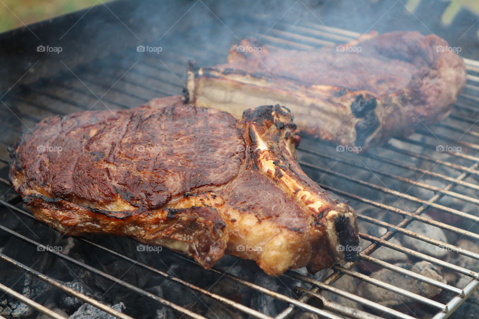 Close up of côte de bœuf steak cooking on bbq