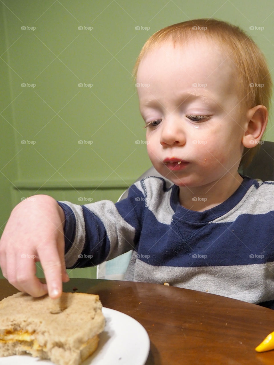 Toddler boy playing with his peanut butter and banana sandwich