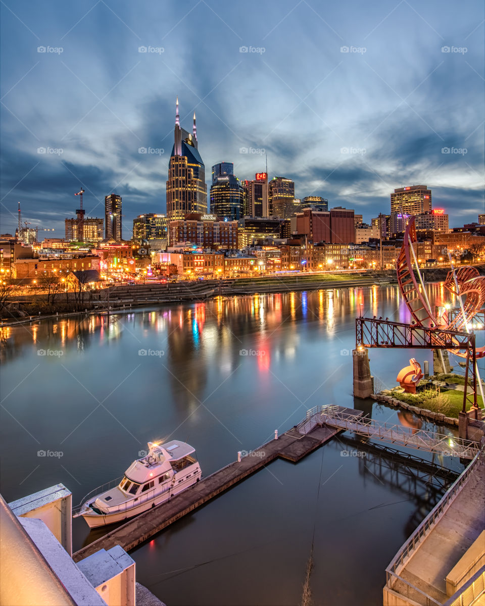 The lights of the downtown Nashville skyline reflecting in the Cumberland River just after the sun set.