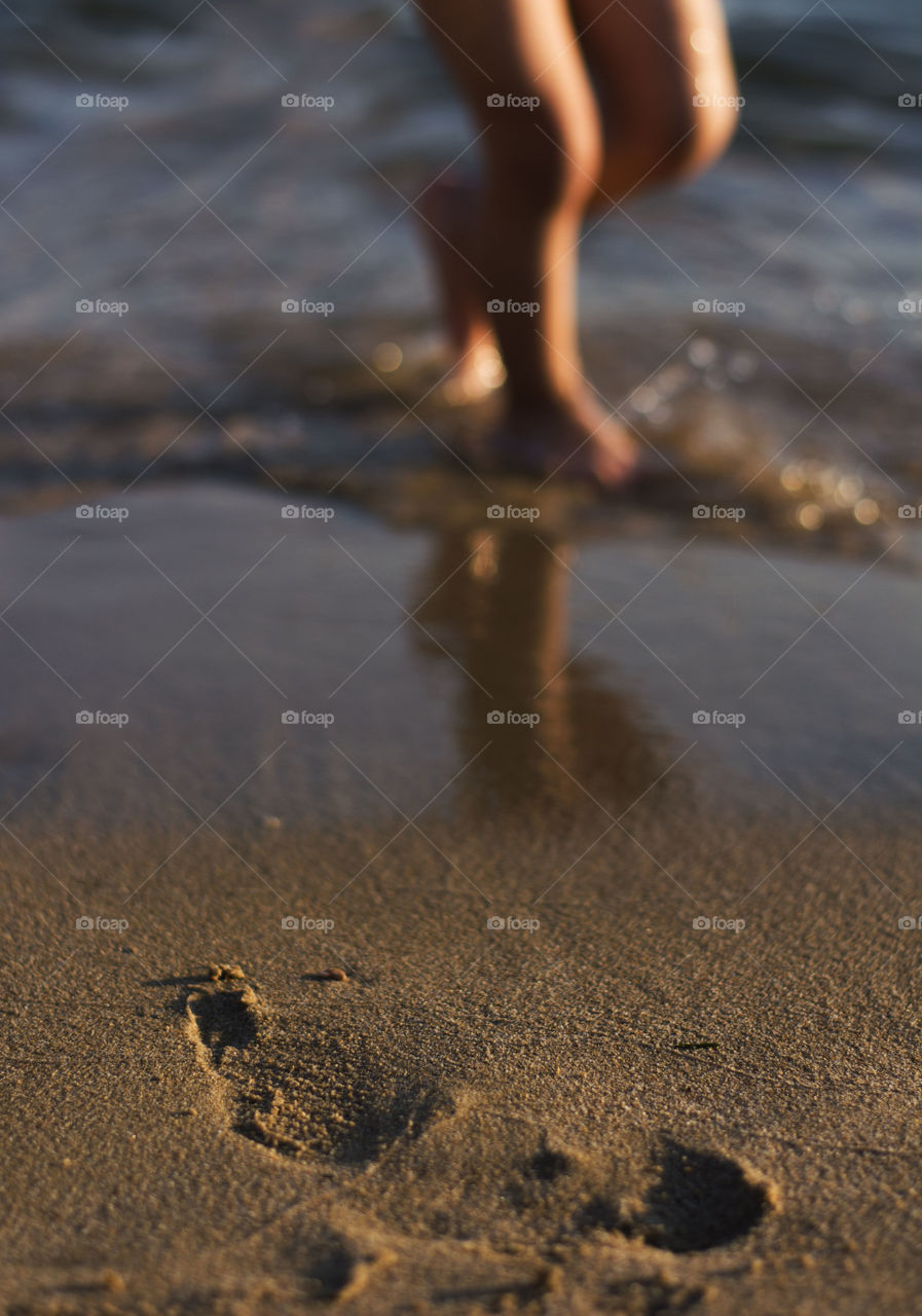 feet in the sand. feet in the water on a sandy beach