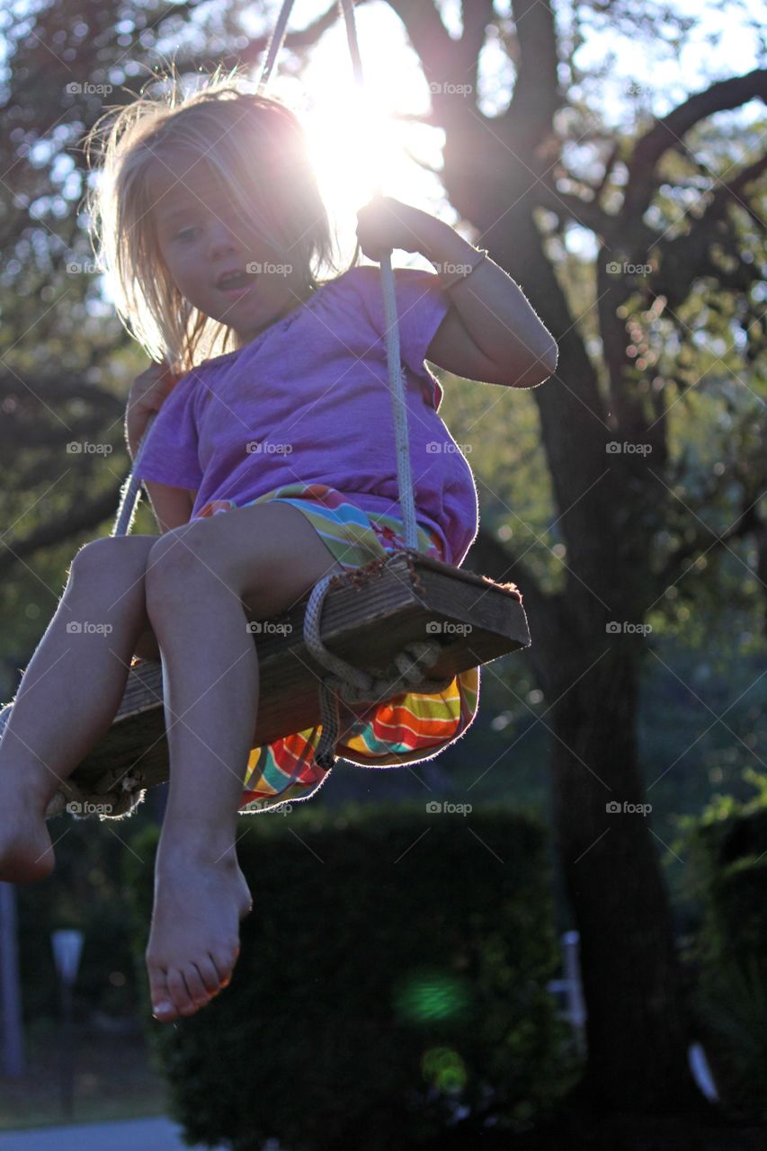 Girl playing on wooden swing