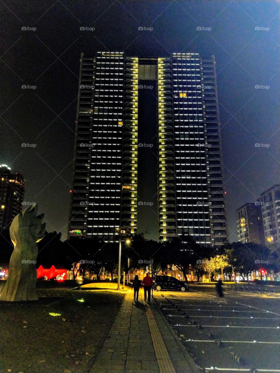 The night view of a twin building is beautiful  and grand from the park in front.