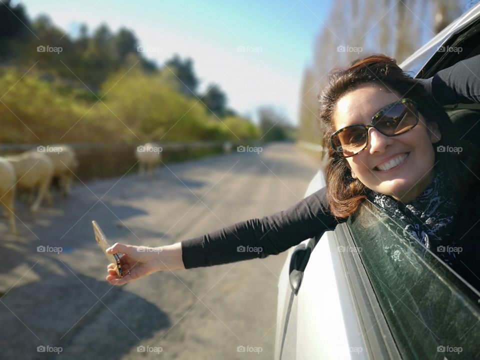 smiling woman traveling by car, greets out the window