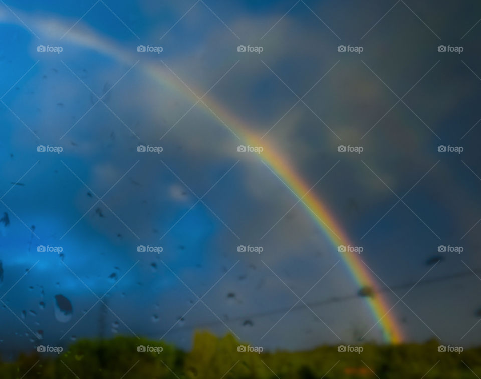 A blurry rainbow seen through wet glass