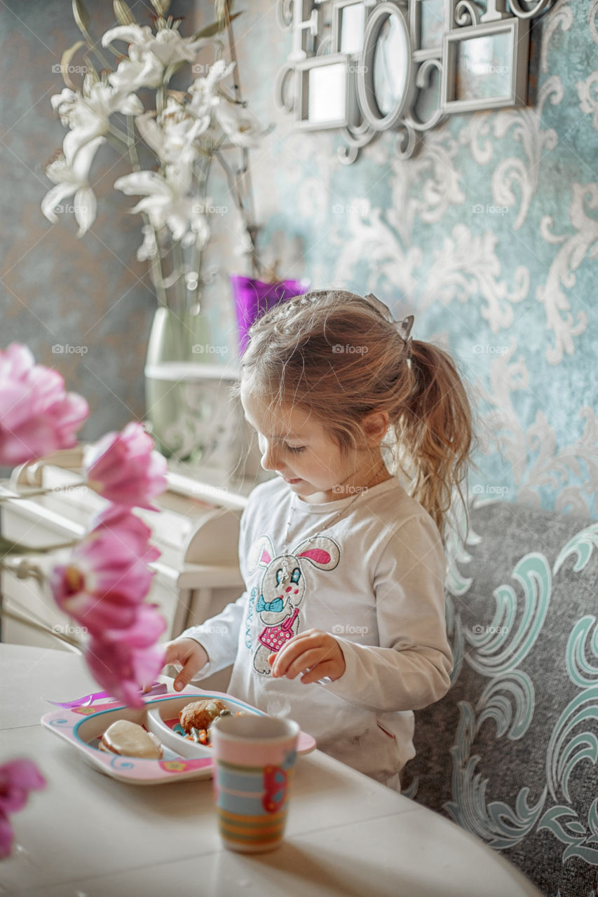 Little girl eating her breakfast in a light kitchen 