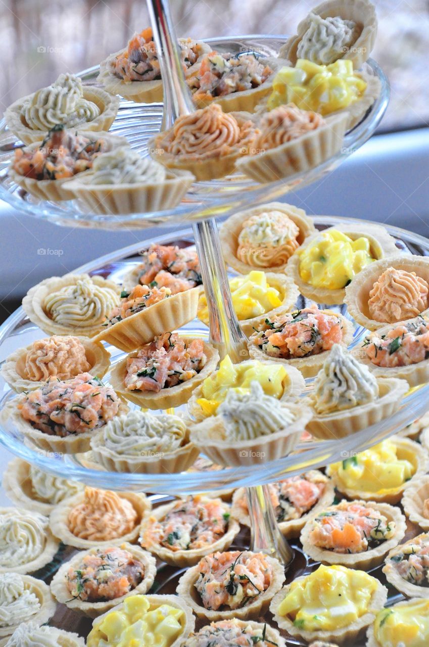 snack tarts with eggpaste salmon herb cheese on three layer glass plate display