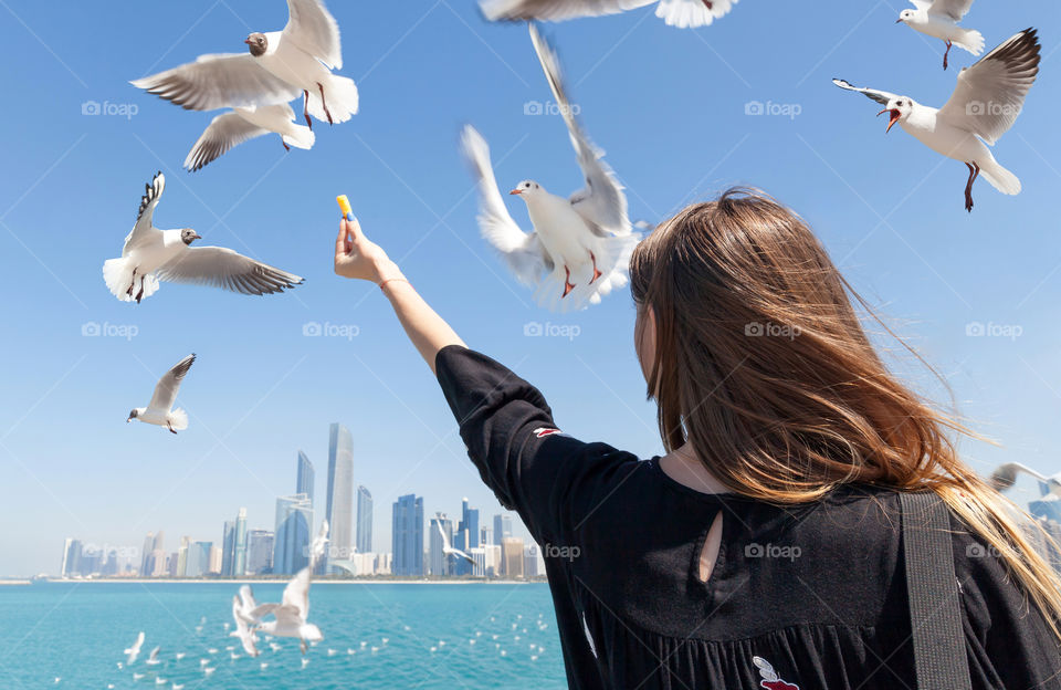 Young woman feeding birds at the beach