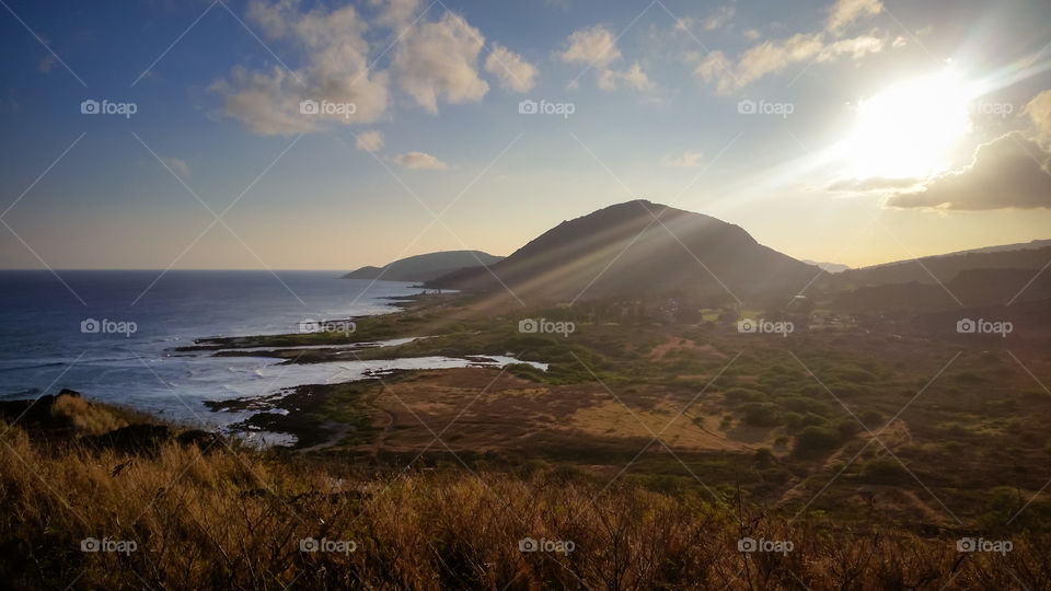 sunrays flooding over a mountain to the beach