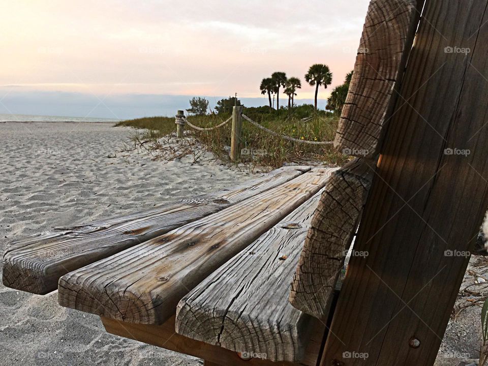 Rustic wooden bench on a beautiful pristine beach.