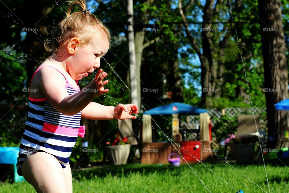 Toddler having fun with water sprinkler