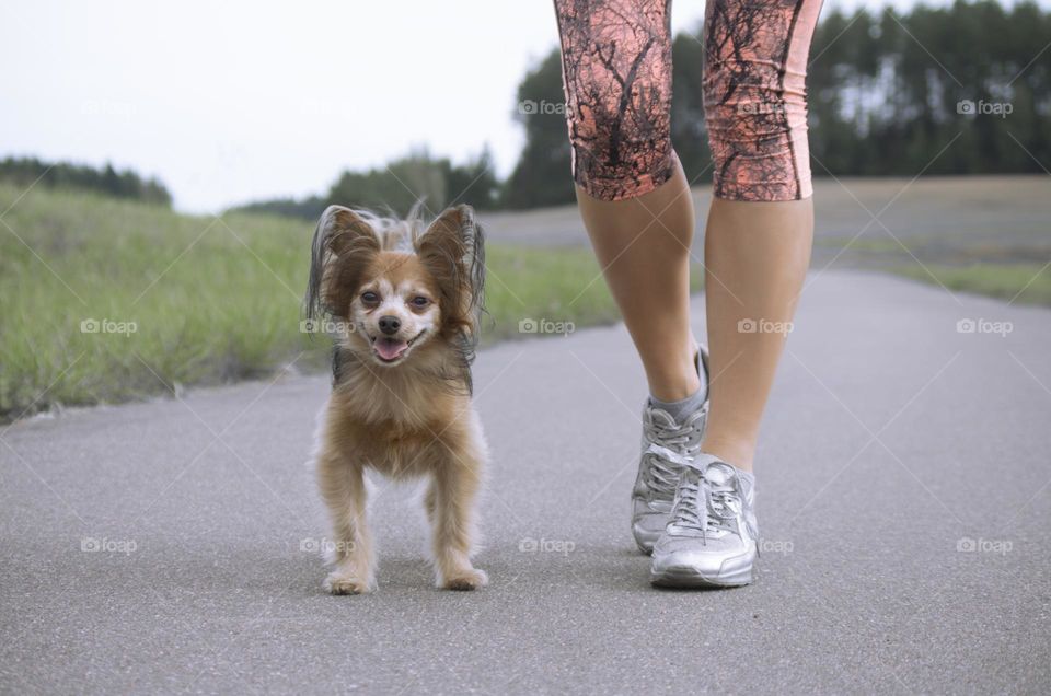 girl running along the road with a dog