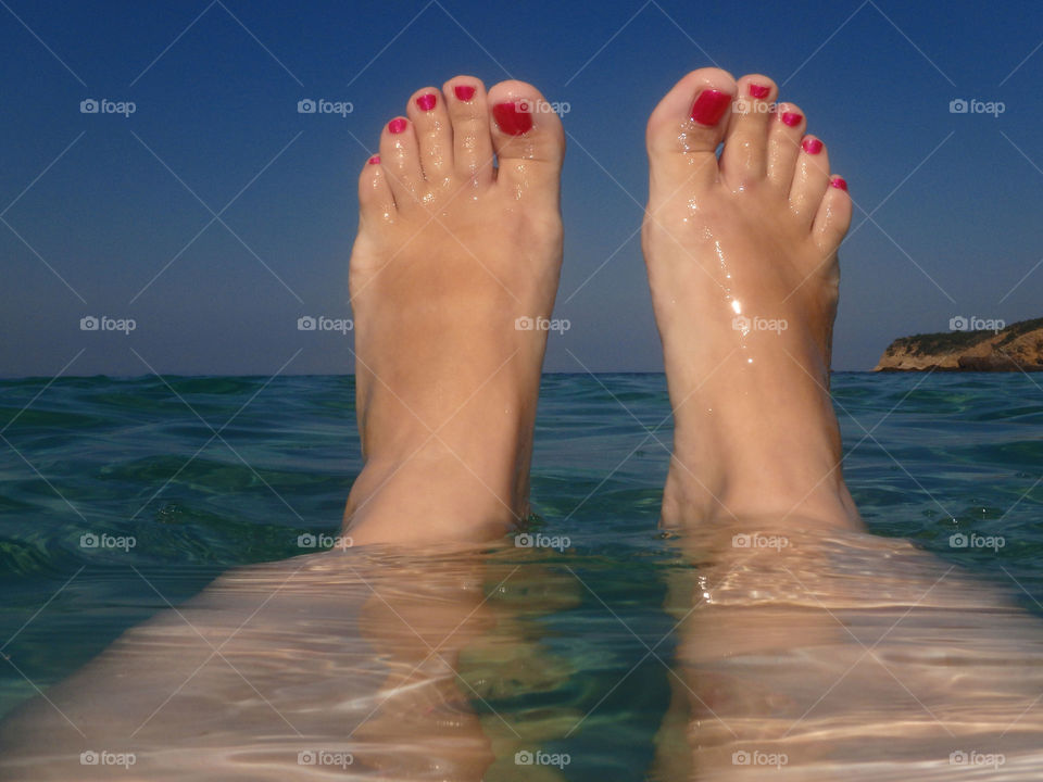 woman feet above sea level. woman feet with red nail polish enjoying sun above the sea level