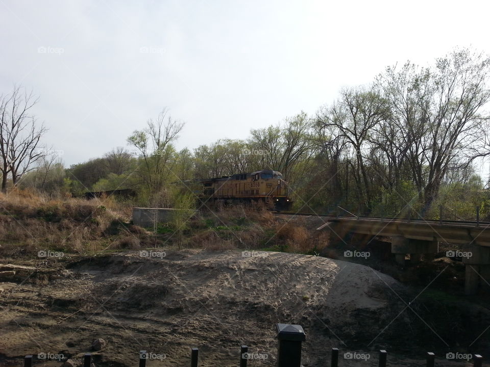 Train Passes By. A train passing by on a bridge over a creek.