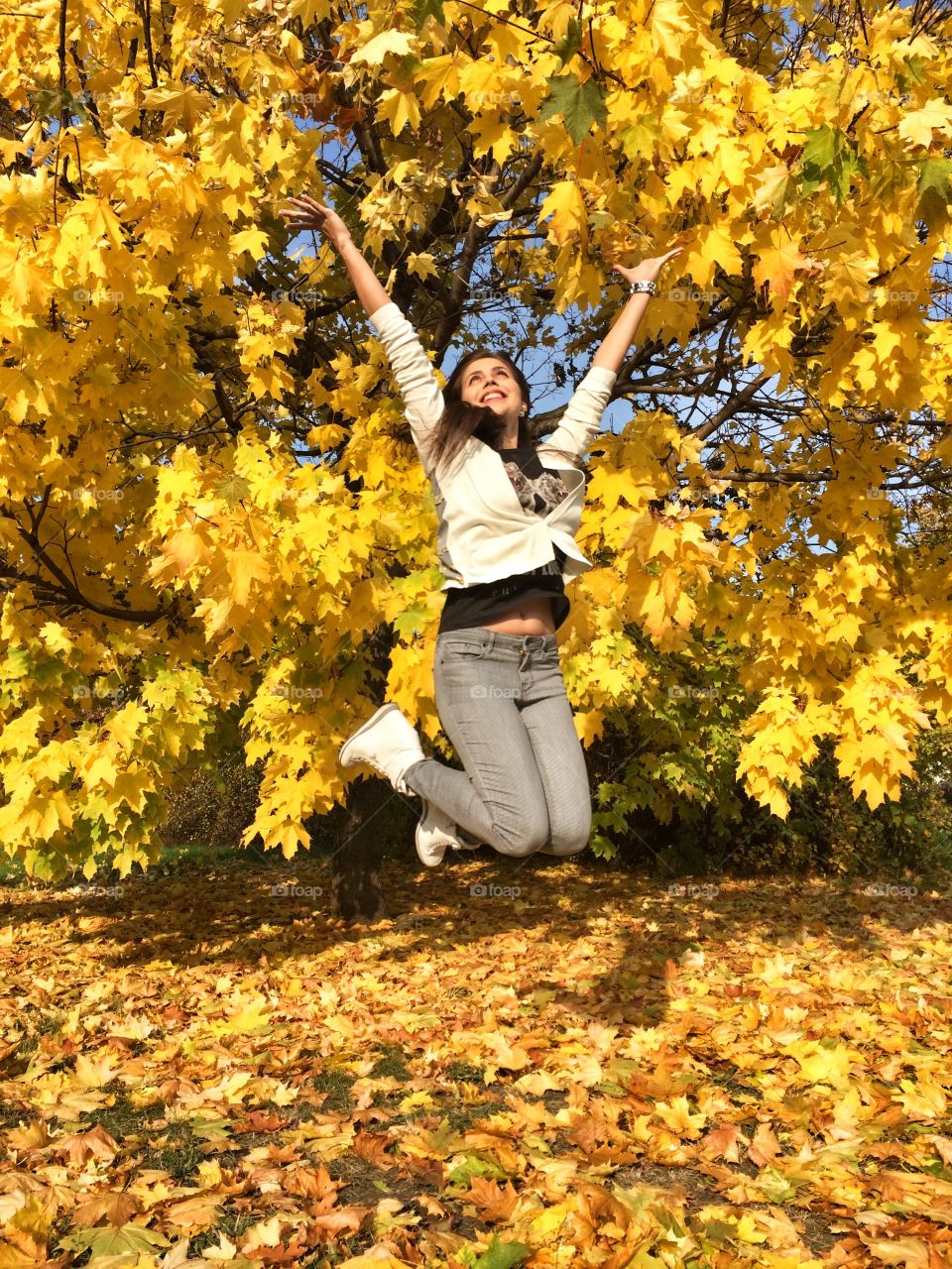 Happy autumn. Smile, shine, be bright. Girl jumping in the golden leaves.
