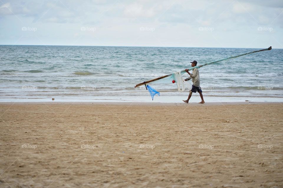 Fisherman walking in the beach 
