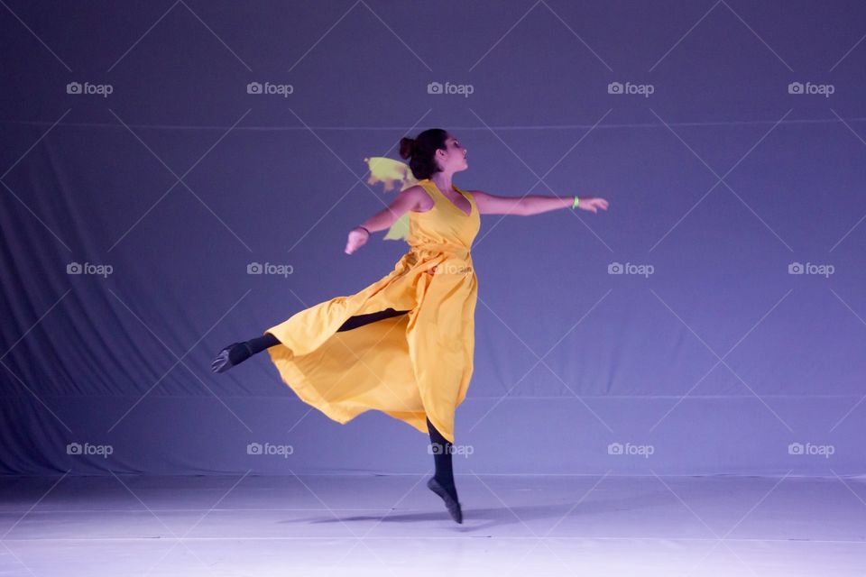 Girl dancing ballet with orange dress, on purple background