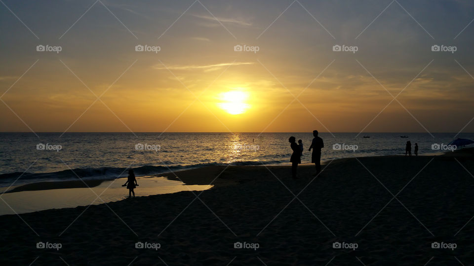family with newborn baby sunset