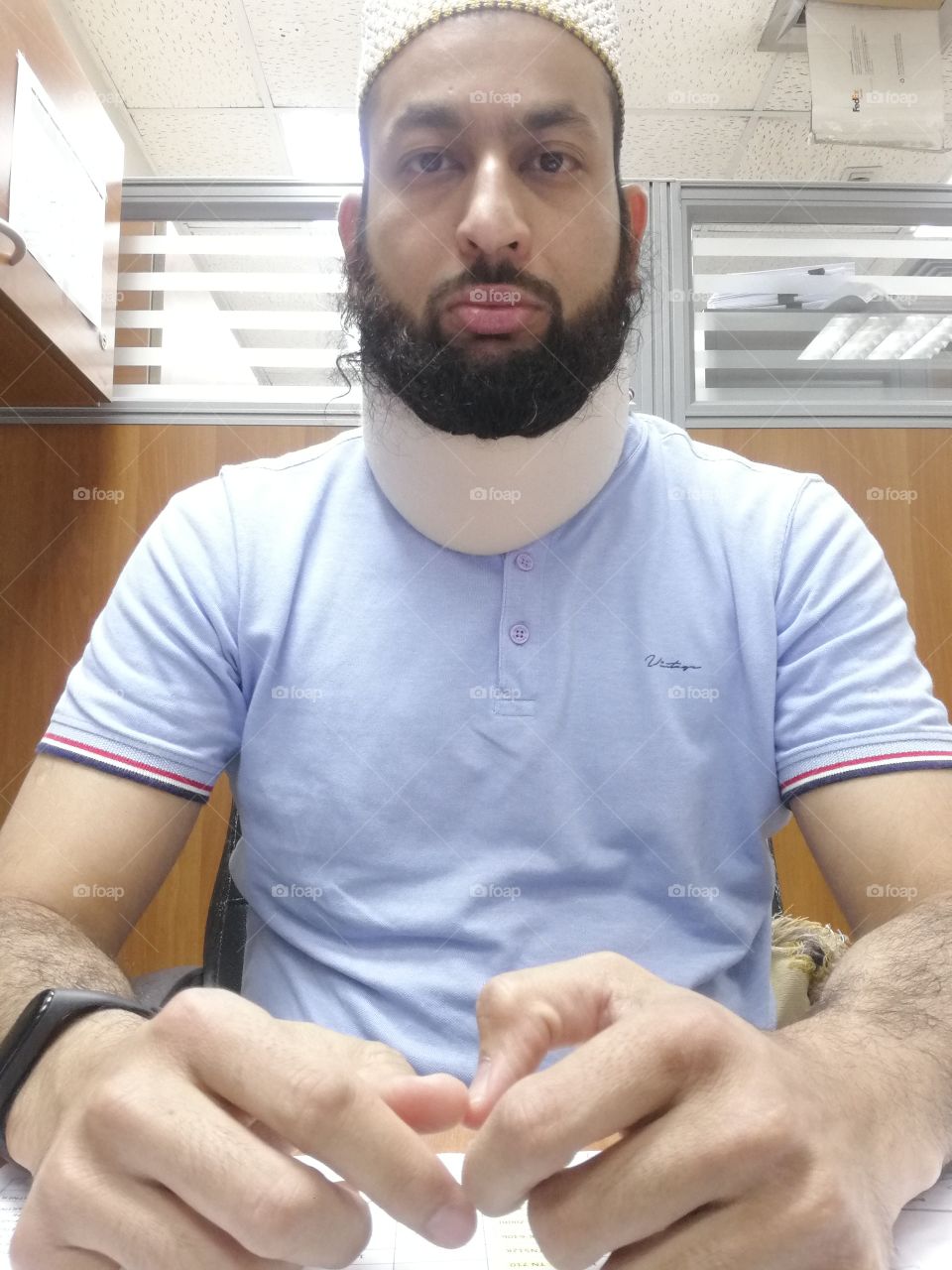 Young Bearded man in tshirt with neck pain collar and fitness band