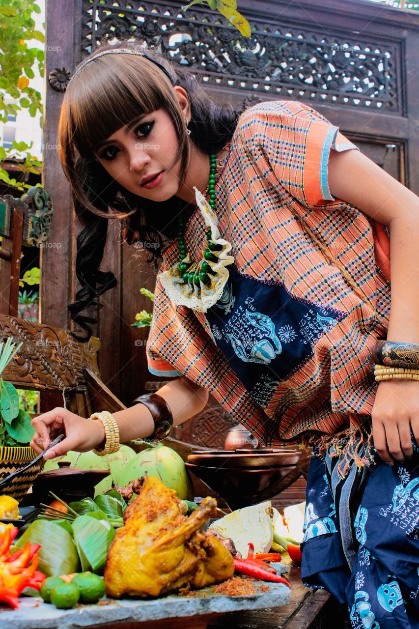 Portrait of young Asian woman in traditional clothing complete with accessories, happy expression.