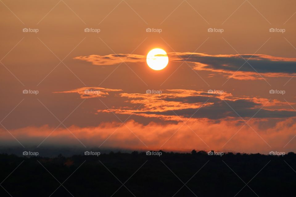 Brilliant fiery orange and red sunset over the Adirondack mountains and lake, clouds and mist 