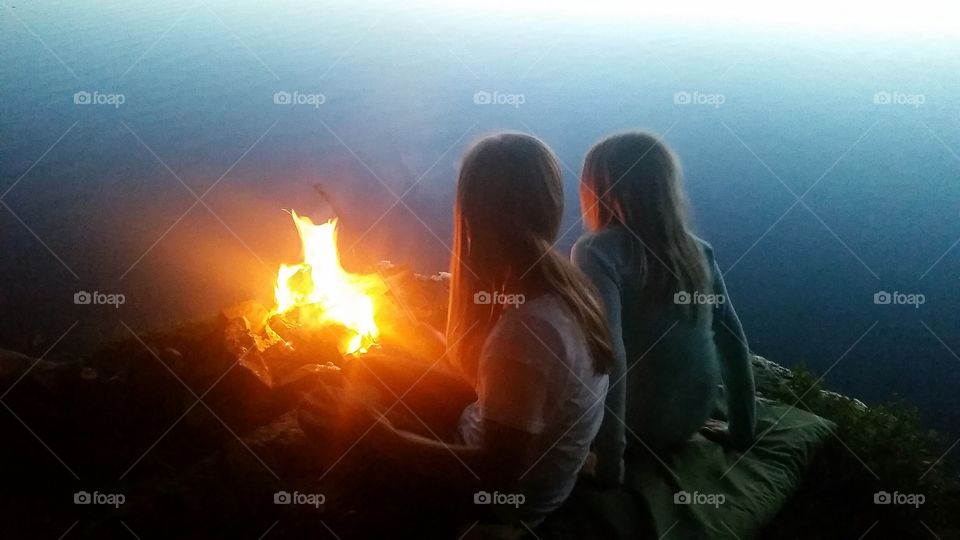 By the camp fire. Two best friends by the camp fire at the lake in the forest.