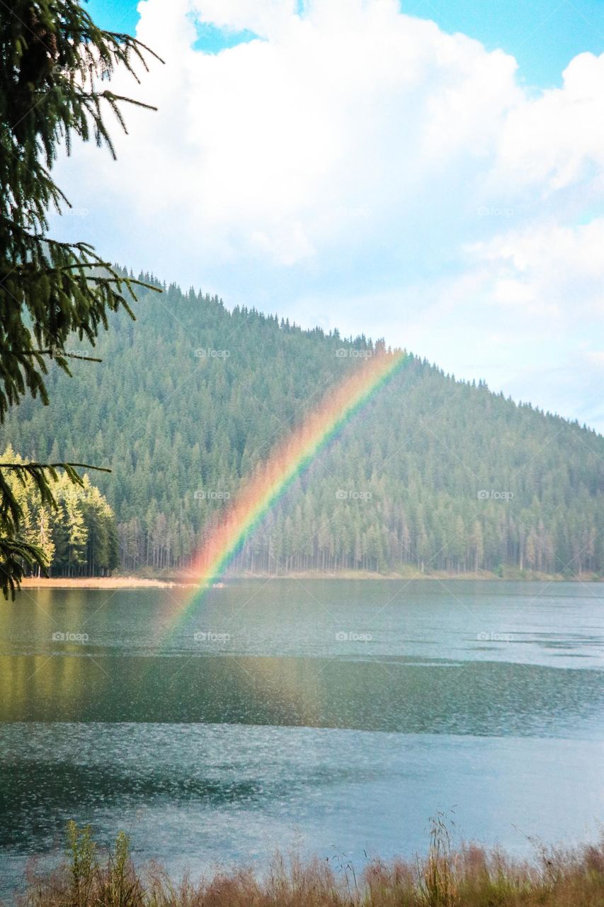 rainbow forming above a lake