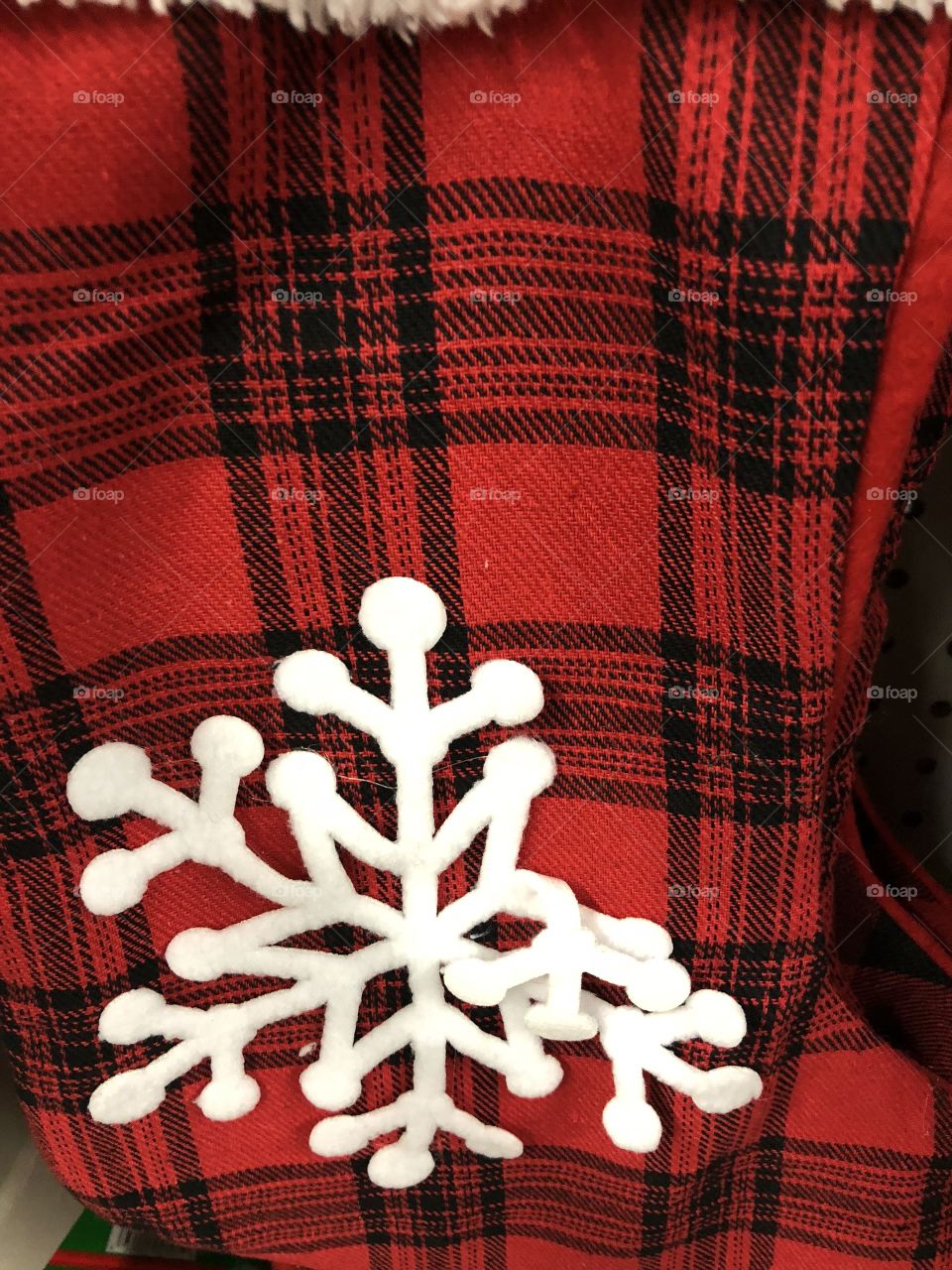 Red plaid fabric with white cut out material snowflake. 