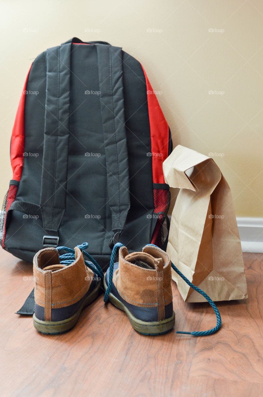 Book bag, shoes and brown paper bag lunch laid out and ready to go for the morning