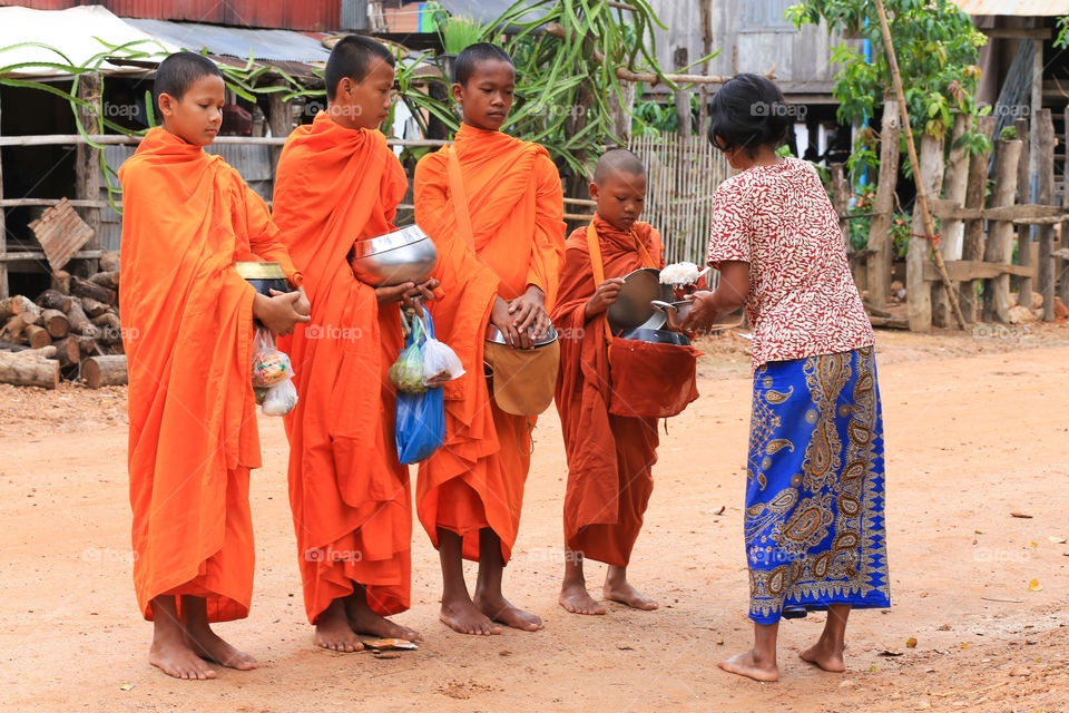 Cambodia monk are orange . Cambodia monk alway walking around villager house work to get a food as Cambodia people they believe in Buddha. 