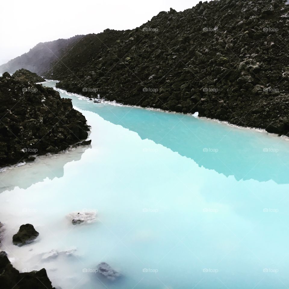 Blue lagoon waters in Iceland and black volcanic rock 