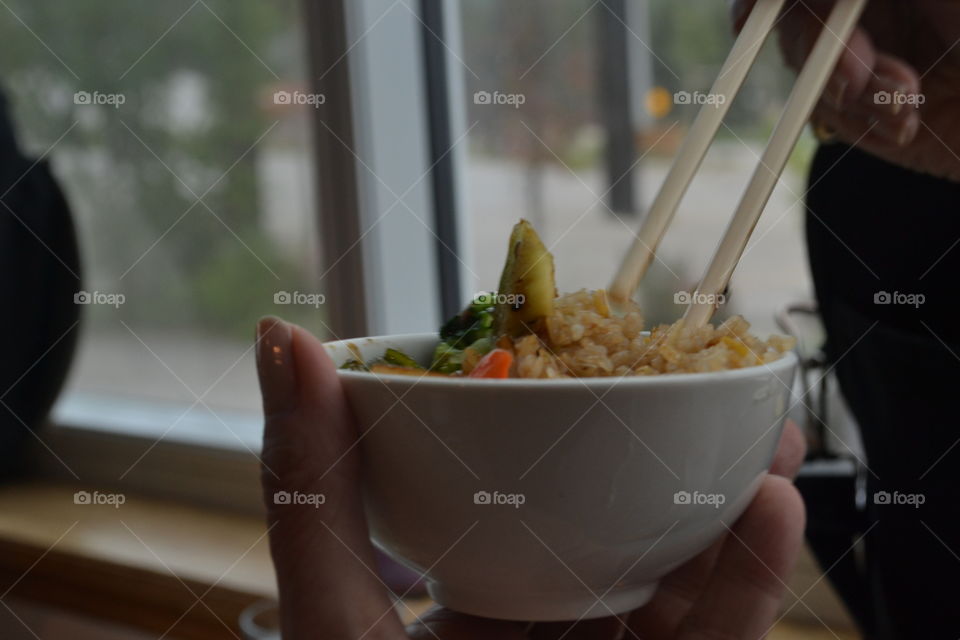 Closeup woman eating Chinese food with chopsticks from bowl