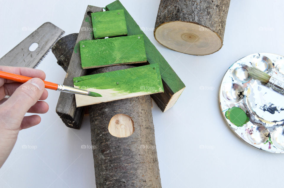 Person creating and painting a decorative birdhouse from scrap wood