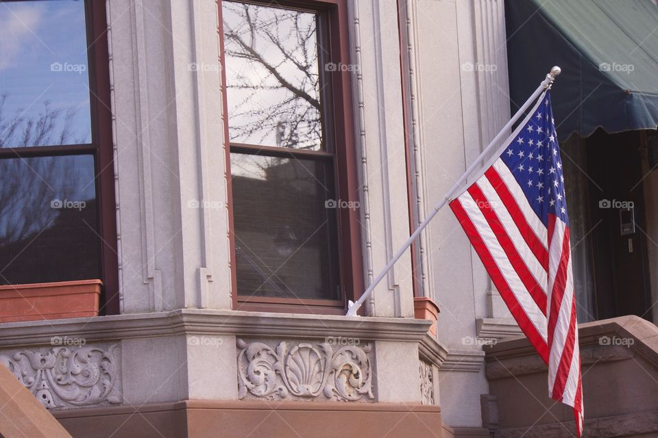 An American flag on a window flag pole of a brownstone home in Park Slope, Brooklyn, NYC.
