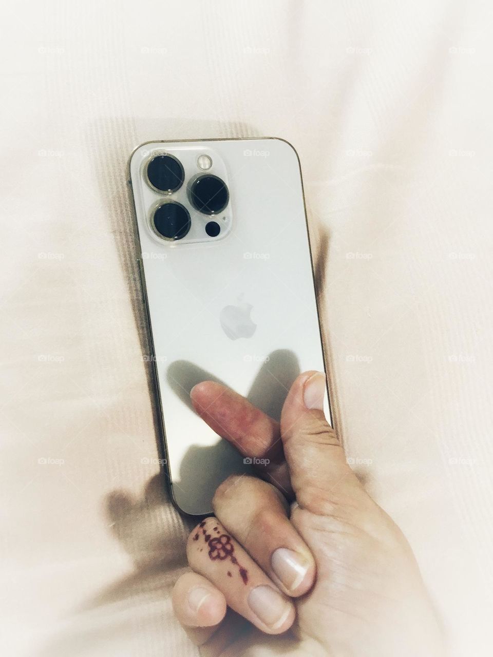 Person expressing love for her iPhone with her fingers by shaping a heart underneath the Apple logo.