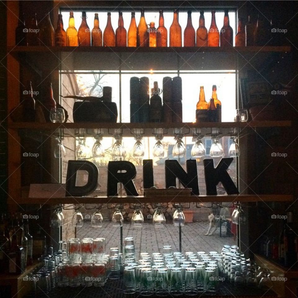 Happy Hour at Seventh Son. Bar window backdrop with glassware, bottles, and word play with sun setting outside 