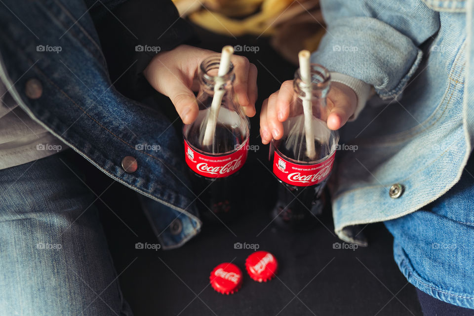 beautiful, stylish, fair-haired children, drinking Coca Cola, eating potatoes, dressed in denim clothes, free photo style.  boy and girl have fun, rejoice, beautiful advertisement for coca cola drink